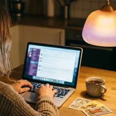Kobieta wpisuje pytanie przy laptopie, obok karty tarota